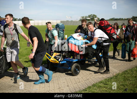 Festivalgoers che arrivano al festival di Glastonbury con il loro equipaggiamento da campeggio su un carrello, a Worthy Farm in Somerset. Foto Stock