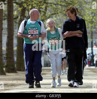 Clare Forbes (centro) di Londra del Sud, che ha fatto amputare entrambe le gambe sotto il ginocchio dopo aver catturato la meningite, attraversando la linea di arrivo della maratona di Londra assistita dal suo padrino Eiffel Verboort (L) e dal vincitore della maratona del 1982 Hugh Jones. Foto Stock