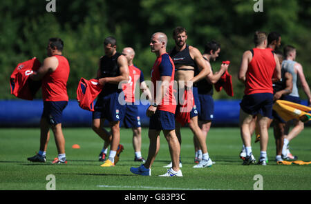 L'allenatore capo dell'Inghilterra Stuart Lancaster guarda i suoi giocatori riscaldarsi prima della sessione di allenamento a Pennyhill Park, Bagshot. Foto Stock