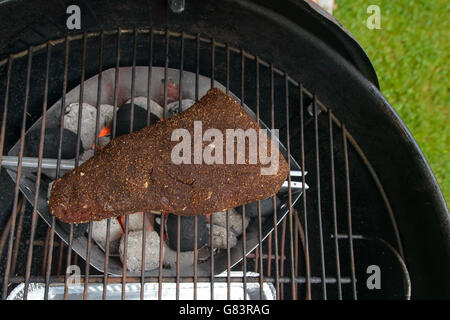 A partire per la cottura alla griglia di un grosso pezzo di carne di manzo in barbecue Foto Stock