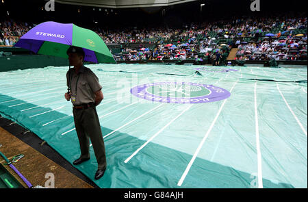 Le fermate della pioggia giocano sul campo centrale durante il 9° giorno del Wimbledon Championships presso l'All England Lawn Tennis and Croquet Club di Wimbledon. Foto Stock