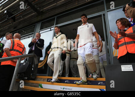 Il capitano australiano Michael Clarke e il capitano inglese Alastair Cook (a destra) guidano i giocatori per l'inizio della prima prova allo stadio SWALEC di Cardiff Foto Stock