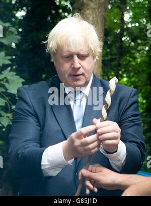 Il sindaco di Londra Boris Johnson avvolge il pane intorno a un bastone prima di cucinarlo su un falò durante una visita a Shooters Hill Woodland presso il Wide Horizons Environment Center, Londra. Foto Stock