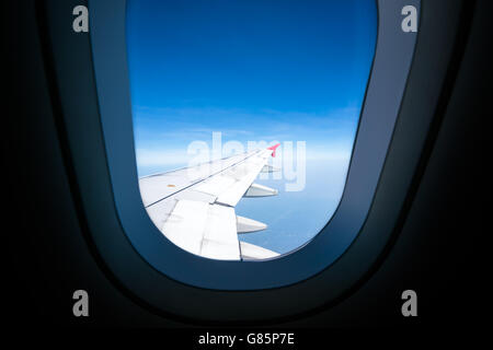 Ala di aeroplano sul cielo blu, vista attraverso il vetro piano, con spazio di copia Foto Stock