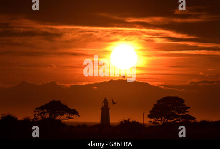 Il sole sorge su Whitley Bay, con la cima del faro di St Mary visibile, mentre l'aria calda e umida dovrebbe essere spinta nel nord Europa questo fine settimana, compresa la Gran Bretagna, creando una 'pianura panish'. Foto Stock