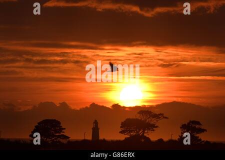 Il sole sorge su Whitley Bay, con la cima del faro di St Mary visibile, mentre l'aria calda e umida dovrebbe essere spinta nel nord Europa questo fine settimana, compresa la Gran Bretagna, creando una 'pianura panish'. Foto Stock