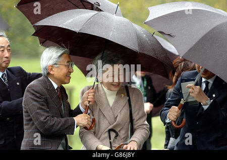 Sua Maestà l'imperatore Akihito del Giappone, con sua moglie, l'imperatrice Michiko, riparo dalla pioggia sotto gli ombrelloni durante una visita alla torre rotonda di San Kevin nel sito monastico come parte della sua visita ufficiale quattro in Irlanda. Foto Stock