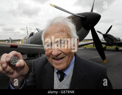 Il veterano della Battaglia di Gran Bretagna, Tony Pickering, leader dello Squadron di Rugby, che ha combattuto insieme ai compagni della seconda guerra mondiale RAF noti come i pochi, ispeziona la medaglia commemorativa della Battaglia di Gran Bretagna 50p della Royal Mint, con un Mark i Spitfire che ha preso parte al conflitto, all'aeroporto Humberside nel Lincolnshire. Foto Stock