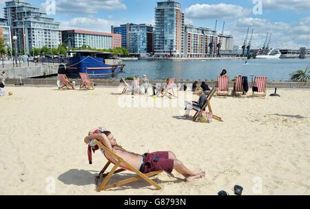 Un uomo si rilassa su una delle sedie a sdraio gratuite e gode del sole sulla spiaggia artificiale all'estremità occidentale del Royal Victoria Docks, a Newham, a est di Londra, dove durante il recente caldo è stata registrata una coda di attesa di 1,000 persone. Foto Stock