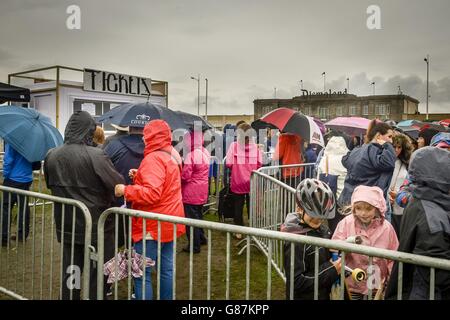 Le persone si accodano sotto la pioggia per acquistare i biglietti per il parco a tema "Dismaland" di Banksy a Weston-super-Mare, Somerset. Foto Stock