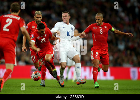 Wayne Rooney in Inghilterra combatte per la palla con Fabian Schar in Svizzera (a sinistra) e Gokhan Inler (a destra) durante la partita di qualificazione europea UEFA al Wembley Stadium di Londra. Foto Stock