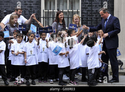 Il primo ministro David Cameron, parla ai bambini delle scuole sui gradini di Downing Street, Londra, mentre attende di salutare l'ex capitano di rugby inglese Martin Johnson e Maggie Alphonsi, parte della squadra femminile dell'Inghilterra che ha vinto la Coppa del mondo nel 2014, Come parte del tour dei trofei della Webb Ellis Cup. Foto Stock