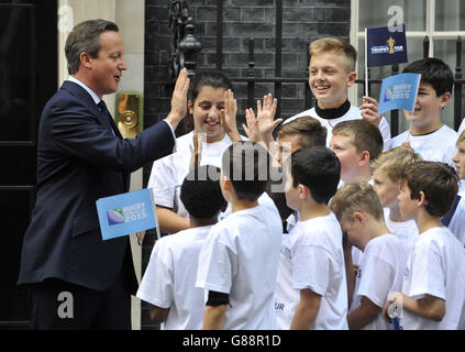 Il primo ministro David Cameron, bambini delle scuole di alto livello sulle scale di Downing Street, Londra, attende di salutare l'ex capitano di rugby inglese Martin Johnson e Maggie Alphonsi, parte della squadra femminile dell'Inghilterra che ha vinto la Coppa del mondo nel 2014, come parte del tour dei trofei della Webb Ellis Cup. Foto Stock