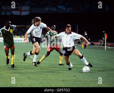 Calcio - Coppa del mondo Italia 1990 - Quarter Final - Inghilterra / Camerun - Stadio San Paolo. Trevor Steven (r) in Inghilterra controlla la palla mentre il compagno di squadra Chris Waddle (secondo l) scoppia oltre Roger Milla (l) del Camerun Foto Stock