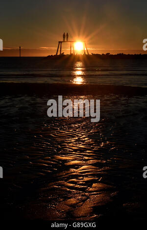 Il sole d'autunno sorge sul mare del nord di fronte alla coppia dell'artista Sean Henry a Newbiggin-by-the-Sea, Northumberland, come condizioni miste e notti più fredde sono in serbo per la Gran Bretagna dopo l'arrivo dell'equinozio d'autunno. Foto Stock