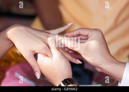 Lo sposo mettendo su anello nuziale indoor Foto Stock