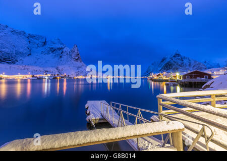 Vette innevate si riflette nel mare freddo al crepuscolo reine isole Lofoten in Norvegia europa Foto Stock