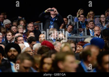 Un delegato scatta una foto prima che il primo ministro David Cameron si recha sul palco per affrontare la conferenza del Partito conservatore a Manchester Central. Foto Stock