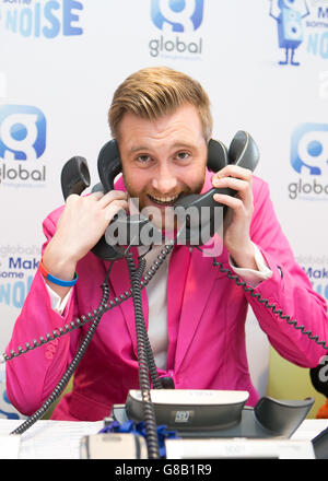 Global's Make some Noise Charity Day. Toby Tarrant, il presentatore della radio propone un'immagine alla 'stanza del telefono' per sostenere Global???'s Make Some Noise presso gli studi globali a Leicester Square, Londra. Global????s Make Some Noise è una carità nazionale che raccoglie denaro per aiutare i giovani svantaggiati e dà voce a piccoli progetti e associazioni di beneficenza in tutto il Regno Unito che lottano per aumentare la consapevolezza. Foto Stock