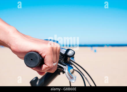 Primo piano di un giovane uomo caucasico in sella ad una bicicletta per il lungomare, con l'oceano sullo sfondo Foto Stock