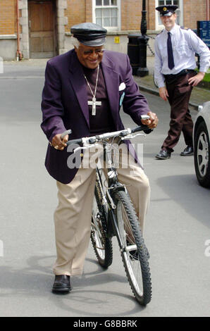 Ex arcivescovo di Città del Capo e vincitore del Premio Nobel per la pace, il dottor Desmond Tutu siede su una bicicletta presa in prestito da uno studente, mentre un membro del Garda Siochana si occupa di dopo essere stato nominato membro onorario della Società filosofica al Trinity College. Foto Stock