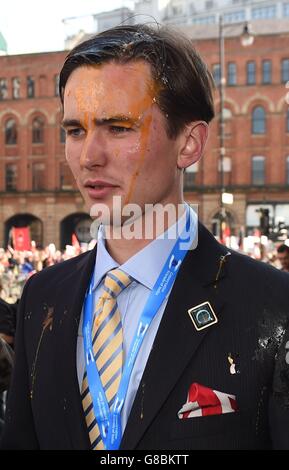 Un giovane delegato Tory dopo essere stato egged dagli attivisti durante una marcia anti-austerità prima dell'inizio della Conferenza del partito conservatore a Manchester. Foto Stock