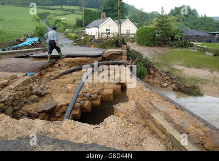 I residenti di Hawnby, nel North Yorkshire guardano il ponte nel loro villaggio dopo che è stato lavato via da inondazioni di notte flash. Nove persone sono state segnalate come scomparse dopo un diluvio nella vicina Helmsley, ma sono state poi trovate sicure e ben. Foto Stock