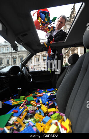 Tim Marlow il direttore artistico della Royal Academy of Arts, deposita una Lego in una berlina BMW serie 5 parcheggiata nel cortile della Royal Academy nel centro di Londra, durante una telefonata per un nuovo progetto artistico internazionale di ai Weiwei. Foto Stock