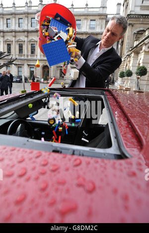 Tim Marlow il direttore artistico della Royal Academy of Arts, deposita una Lego in una berlina BMW serie 5 parcheggiata nel cortile della Royal Academy nel centro di Londra, durante una telefonata per un nuovo progetto artistico internazionale di ai Weiwei. Foto Stock