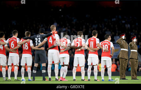 Gli Arsenali insieme ai rappresentanti delle forze armate (destra) si levano in piedi Per un minuto di silenzio prima del calcio d'inizio della Domenica della memoria Foto Stock