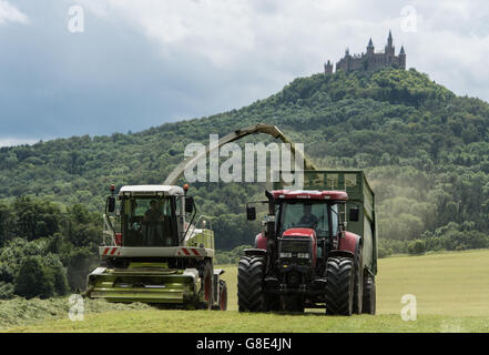 Bisingen, Germania. Il 28 giugno, 2016. Un cosiddetto trincia erba e un trattore raccolta erba per alimentazione del bestiame, con Hohenzollern Castello raffigurato in background, vicino a Bisingen, Germania, 28 giugno 2016. Foto: PATRICK SEEGER/dpa/Alamy Live News Foto Stock