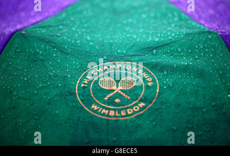 Una marca di Wimbledon ombrello è coperto in caso di pioggia il giorno Due dei campionati di Wimbledon al All England Lawn Tennis e Croquet Club, Wimbledon. Foto Stock