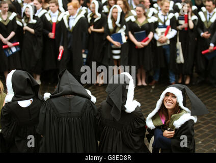 Università di Edimburgo gli studenti riparo dalla pioggia come hanno fotografie ufficiali presi dopo la loro cerimonia di laurea alla Usher Hall di Edimburgo. Foto Stock