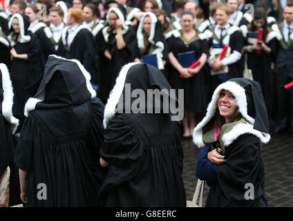 Università di Edimburgo gli studenti riparo dalla pioggia come hanno fotografie ufficiali presi dopo la loro cerimonia di laurea alla Usher Hall di Edimburgo. Foto Stock