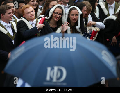 Università di Edimburgo gli studenti riparo dalla pioggia come hanno fotografie ufficiali presi dopo la loro cerimonia di laurea alla Usher Hall di Edimburgo. Foto Stock