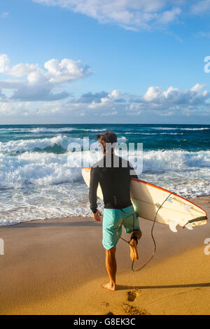 Surfer va verso il mare a Hookipa Beach a Maui Foto Stock