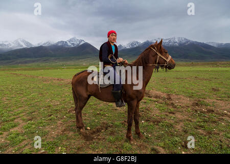 Il cavaliere nomade riposa sul cavallo dopo i tradizionali giochi nomadi nel lago Issyk Kul, Kirghizistan. Foto Stock