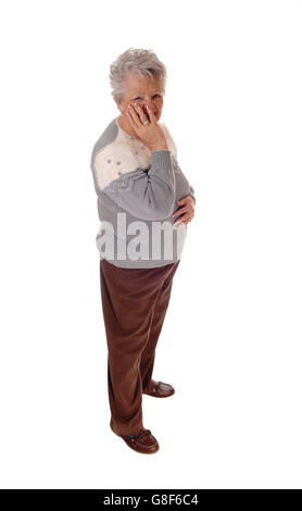 Un vecchio senior citizen donna in piedi isolato per sfondo bianco tenendo una mano sul suo viso. Foto Stock