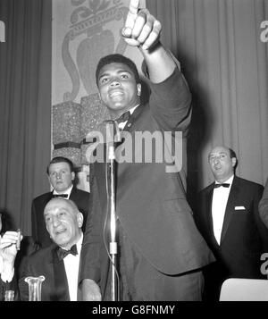 Muhammad Ali punta attraverso la stanza e chiama Henry Cooper al London Hilton Hotel in Park Lane, dove il campione del mondo è stato ospite d'onore ad una cena di pugilato del Club Sportivo anglo-americano. "Se fosse qui, lo combattevo ora" dichiarò Ali. Cooper lo sfiderà per il titolo mondiale all'Arsenal Stadium il 21 maggio. Foto Stock