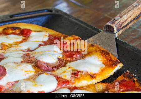 Close up od una forcella di legno in una pizza con salsiccia per pizza Foto Stock