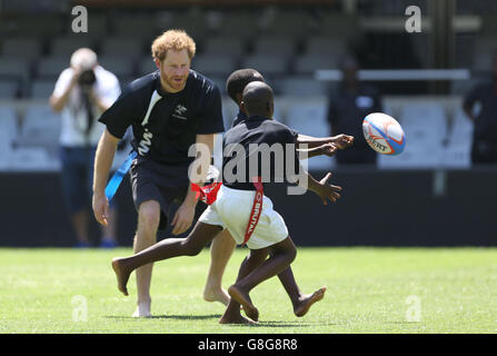 Il principe Harry gioca a tag rugby con i bambini al Kings Park Stadium mentre si unisce ai membri della squadra di rugby Sharks sul campo a Durban, in una sessione di addestramento e di abilità con allenatori e giovani giocatori come parte della sua visita in Sud Africa. Foto Stock