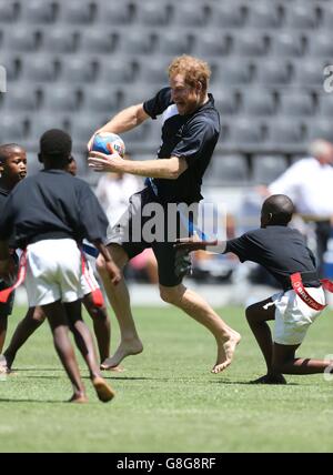 Il principe Harry gioca a tag rugby con i bambini al Kings Park Stadium mentre si unisce ai membri della squadra di rugby Sharks sul campo a Durban, in una sessione di addestramento e di abilità con allenatori e giovani giocatori come parte della sua visita in Sud Africa. Foto Stock