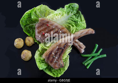 Costolette di agnello con pomodoro, pane, foglie di insalata Foto Stock