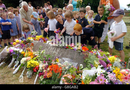 I bambini della Wilden All Saints School continuano una tradizione secolare mentre posano fiori nella tomba di un cowman morto nel 1899. Thomas Jones lasciò tutta la sua proprietà ai figli del villaggio a condizione che cantassero una canzone e posassero fiori sulla sua tomba nel villaggio Worcestershire di Wilden il suo compleanno, giorno di San Swithen, ogni anno. Foto Stock