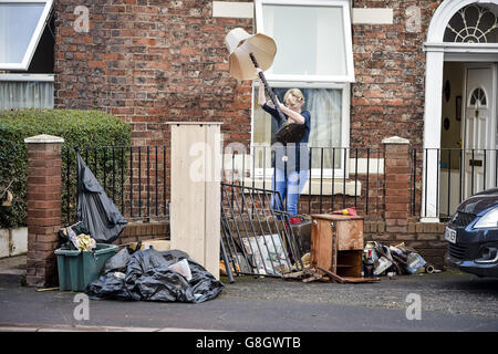 Le persone ripuliscono le loro case di proprietà danneggiate dall'acqua mentre la pulizia inizia su Warwick Road dopo le inondazioni a Carlisle. Foto Stock