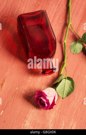 Svuotare la bottiglia di rosso e una rosa rosa Foto Stock