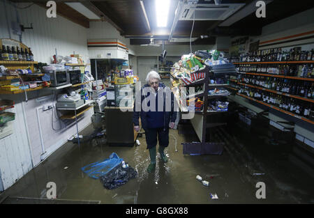 Allan John Brown esamina i danni causati al Glenridding Mini Market dopo che il fiume nella città di Cumbria ha fatto esplodere di nuovo le sue rive dopo le continue precipitazioni della notte scorsa. Foto Stock