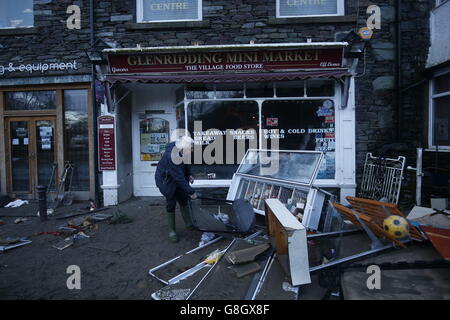 Allan John Brown esamina i danni causati al Glenridding Mini Market dopo che il fiume nella città di Cumbria ha fatto esplodere di nuovo le sue rive dopo le continue precipitazioni della notte scorsa. Foto Stock