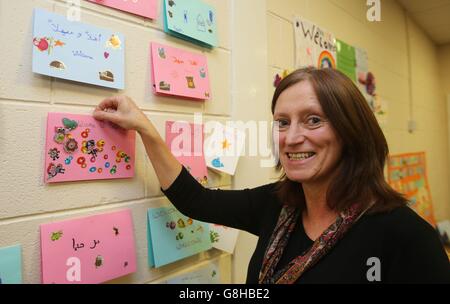 Denise Wright, presidente del Forum per i rifugiati e l'asilo, appende le schede fatte a mano dai bambini delle scuole locali sulle pareti di un centro di accoglienza in un luogo non divulgato a Belfast che fornirà alloggio temporaneo per il primo gruppo di rifugiati siriani a reinsediarsi nell'Irlanda del Nord. Foto Stock