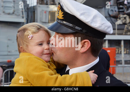 Il comandante del tenente Nick London, 35, da Alverstoke, Hampshire, dà alla figlia Rosalie, 2, un bacio mentre ritorna a bordo della HMS Lancaster alla base navale di Portsmouth dopo che la Royal Navy Frigate ha completato un viaggio di 35,000 miglia attraverso quattro oceani. Foto Stock